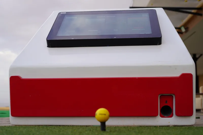 Tablette Prime Golf et balle jaune posée sur tee de practice